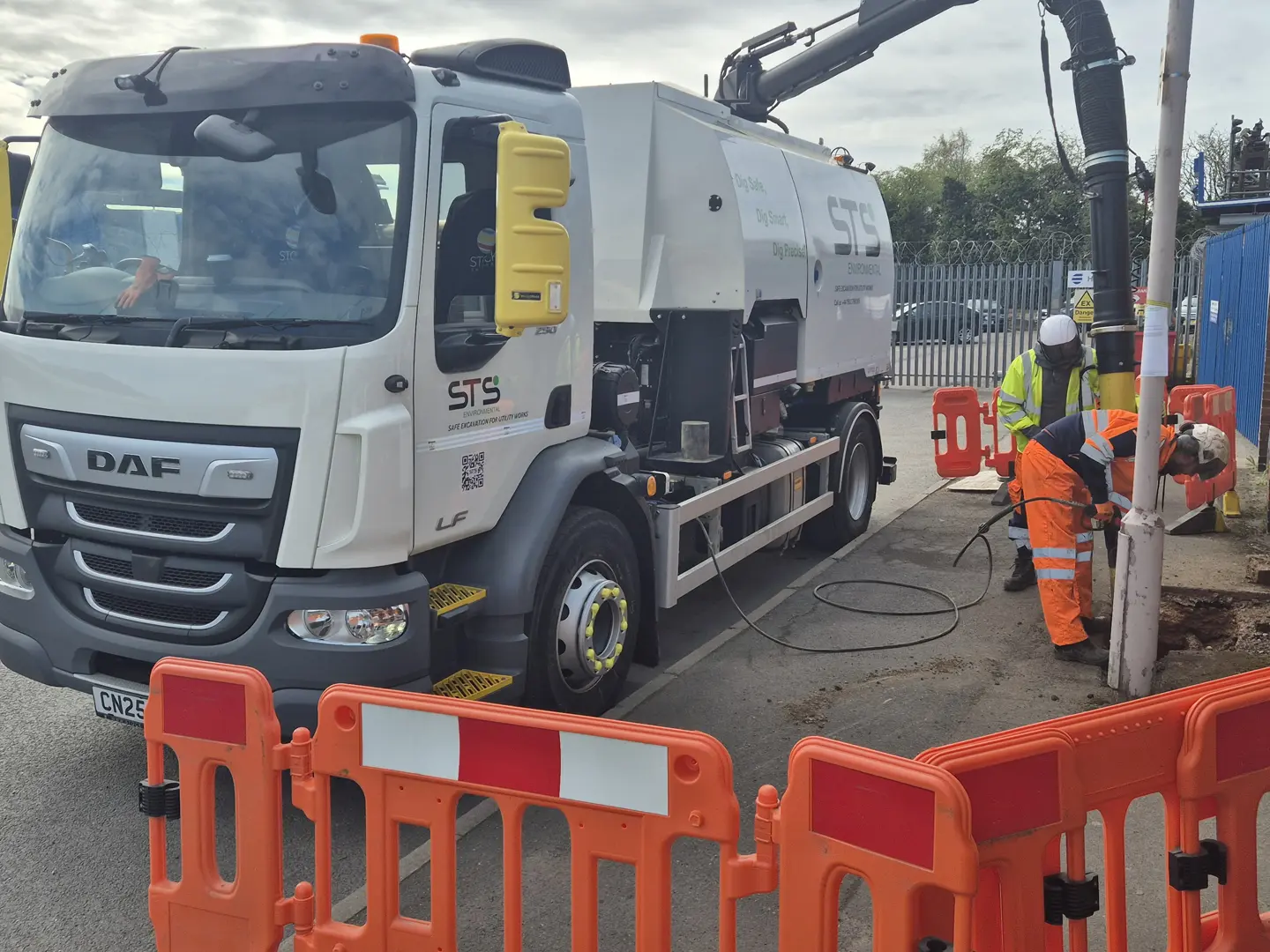 Construction workers using high-pressure water and vacuum for safe utility excavation